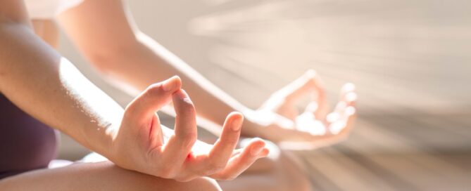 Foto em close das mãos de uma mulher em posição de lótus da yoga
